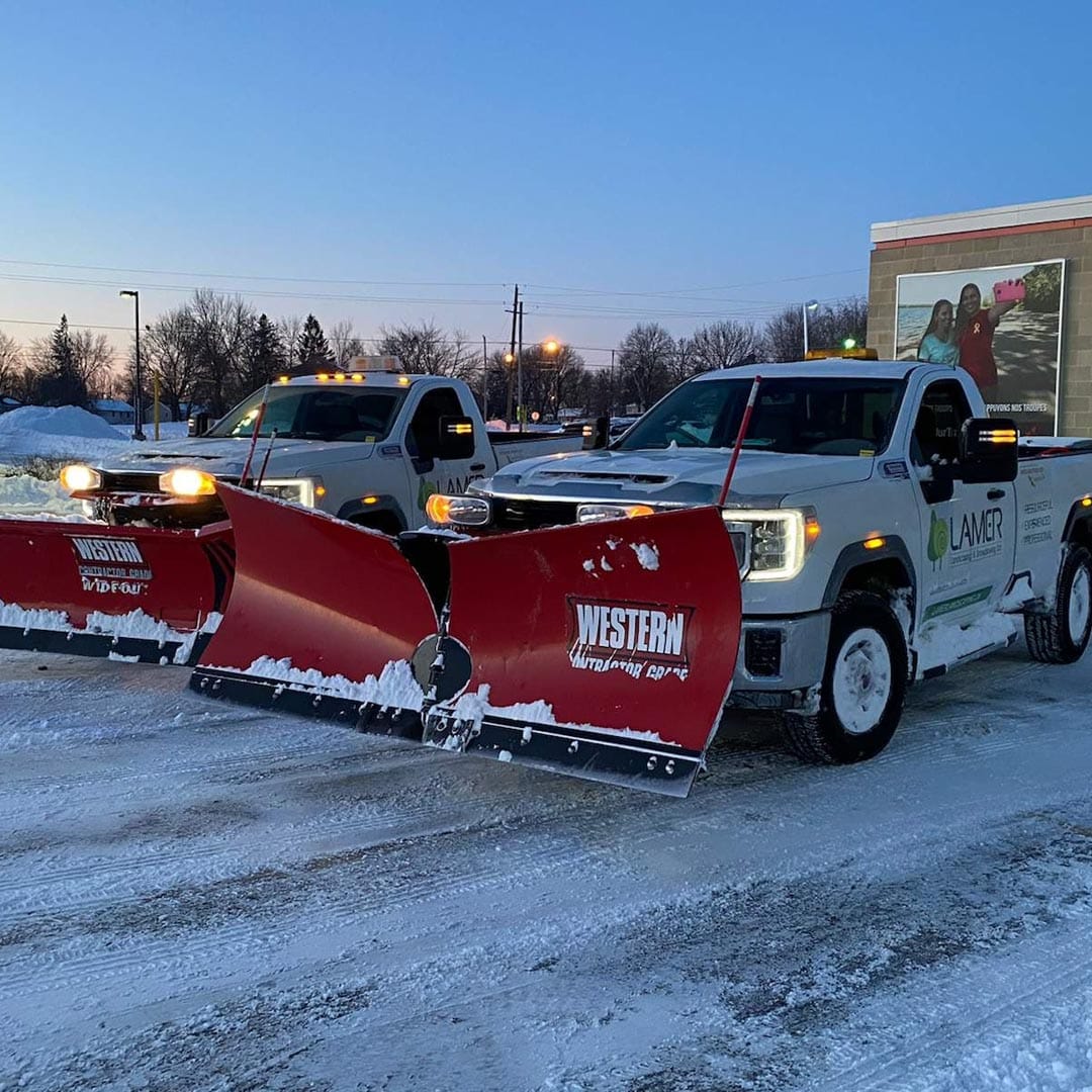 Lamer pickup trucks fitted with snow plows before a winter route